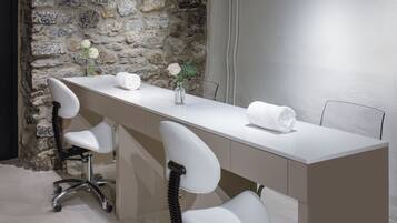 Un baño moderno con pared de piedra, encimera blanca y tres sillas blancas.