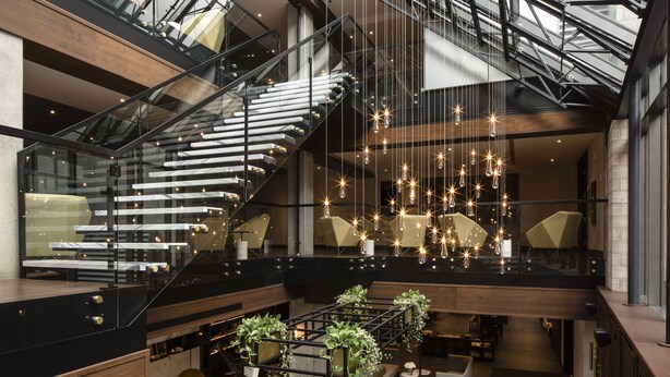 Ein modernes Interieur mit Treppe, Sitzbereichen und Pendelleuchten.