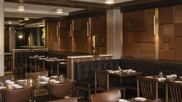 A restaurant interior with booth seating, tables, and a bar area.