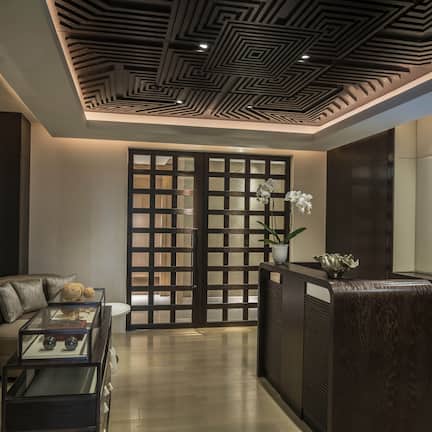 A modern interior with a reception desk, a sofa, and a decorative wall piece.
