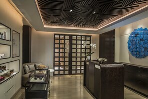 A modern interior with a reception desk, a sofa, and a decorative wall piece.