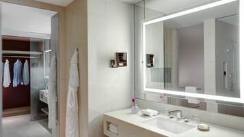 A modern bathroom with a large mirror, a sink, and a towel rack.