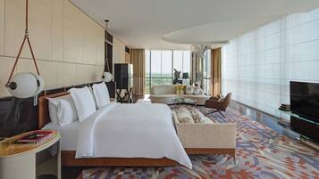 A hotel room with a large bed, a sofa, a TV, and a view of the city.