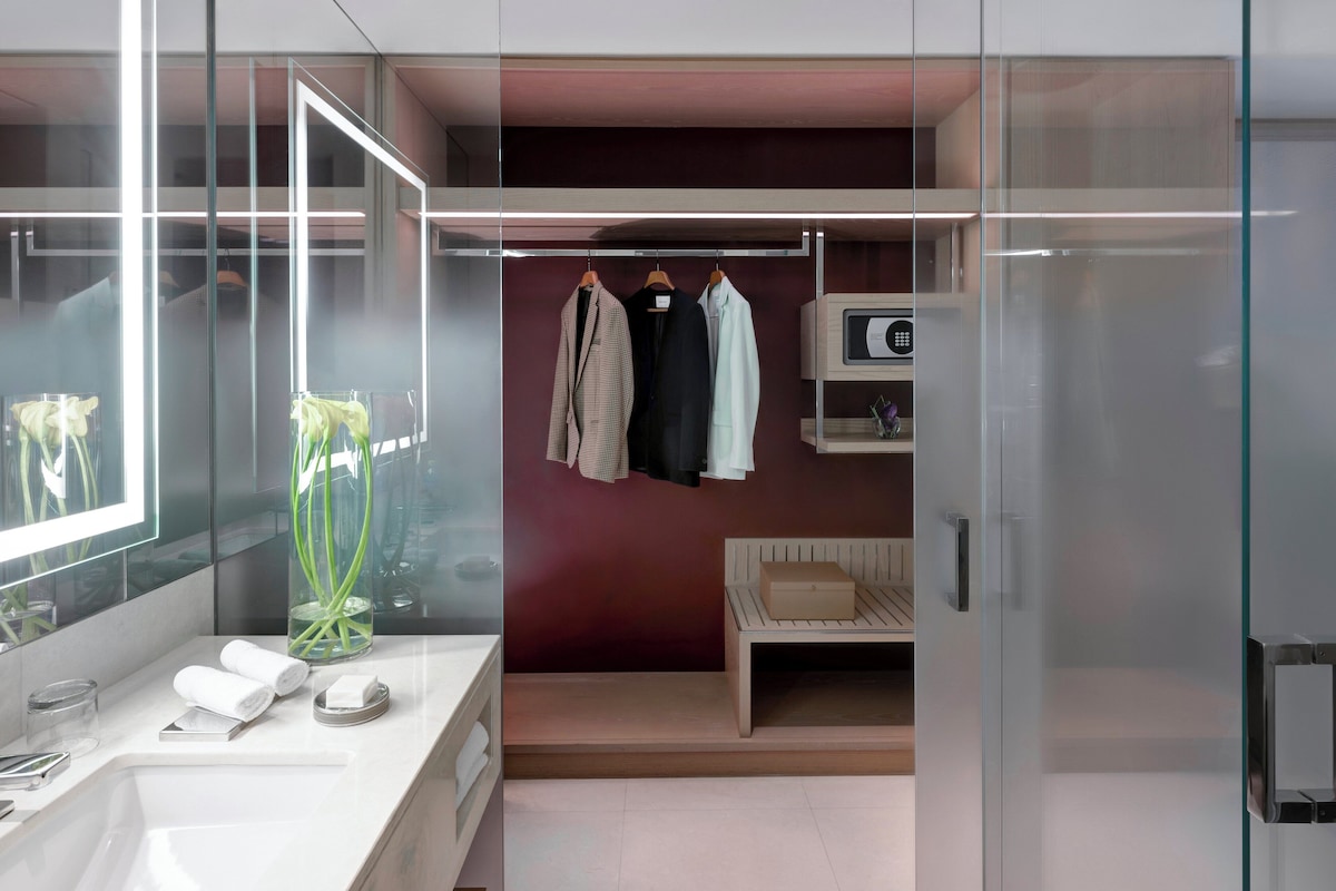 A modern bathroom with a large mirror, a white sink, and a glass shower enclosure.
