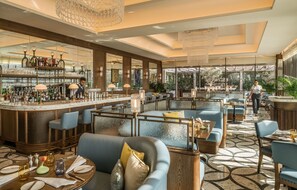 A bar area with a counter, stools, and a seating area with sofas and tables.
