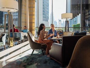 A modern hotel room with a city view, a dining area, and a lounge with comfortable seating.