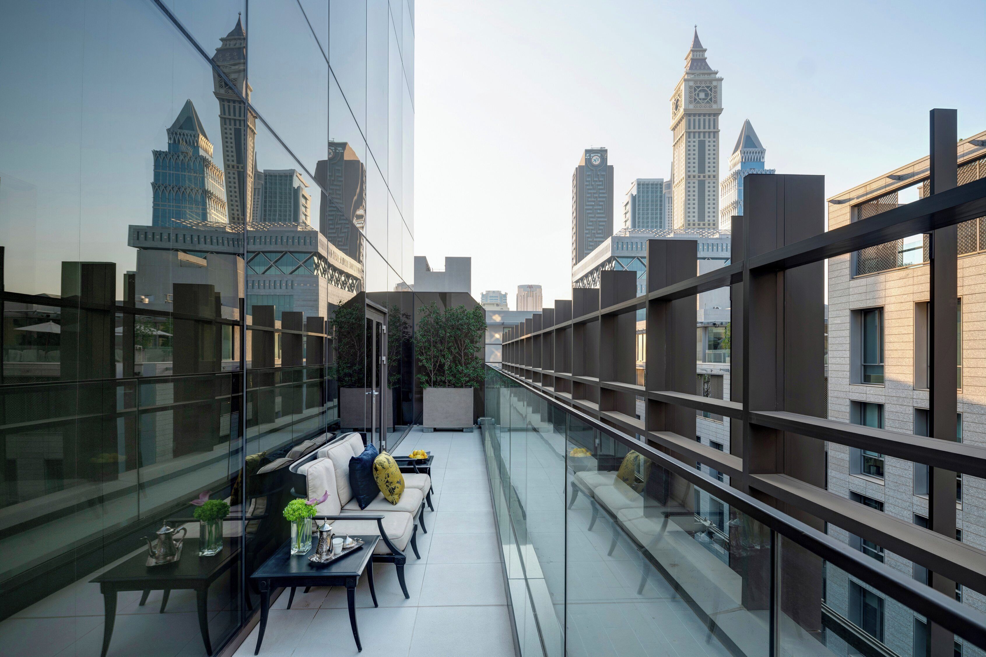 Terraço moderno no telhado com guarda-corpo de vidro, área de estar e vista para o horizonte da cidade.