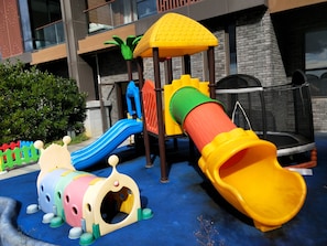 Zona de juegos infantiles con tobogán, estructura de escalada y un túnel pequeño.