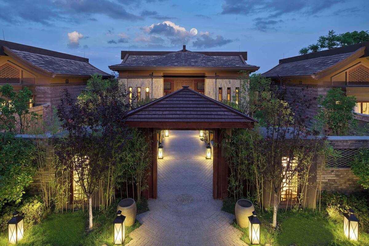 A two-story building with a central entrance, surrounded by a garden with lanterns and a brick pathway.