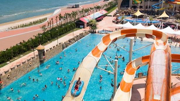 Un parc aquatique doté d’une grande piscine, de toboggans et d’une zone aménagée en plage.