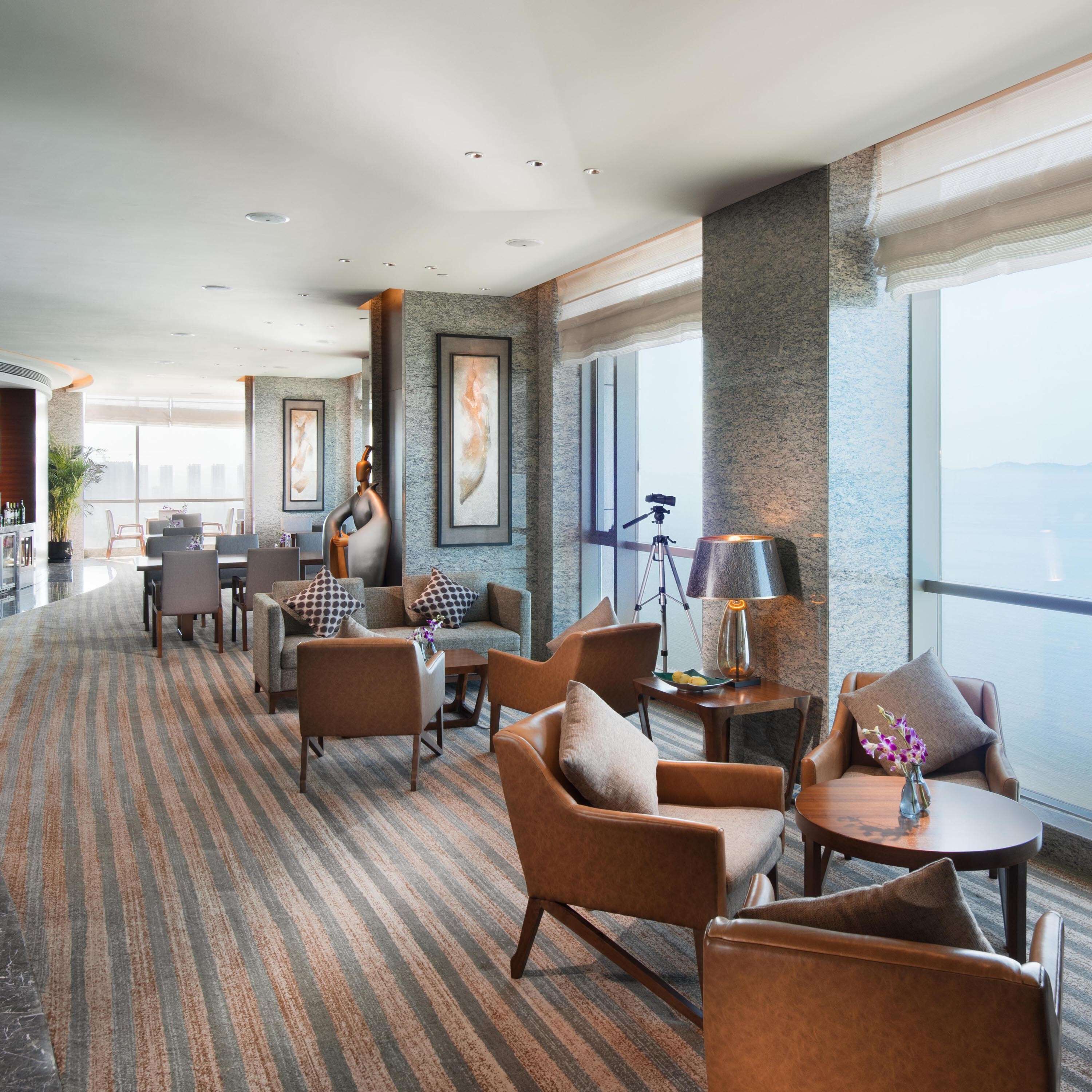 A spacious lounge with comfortable seating, a bar area, and large windows offering a view.
