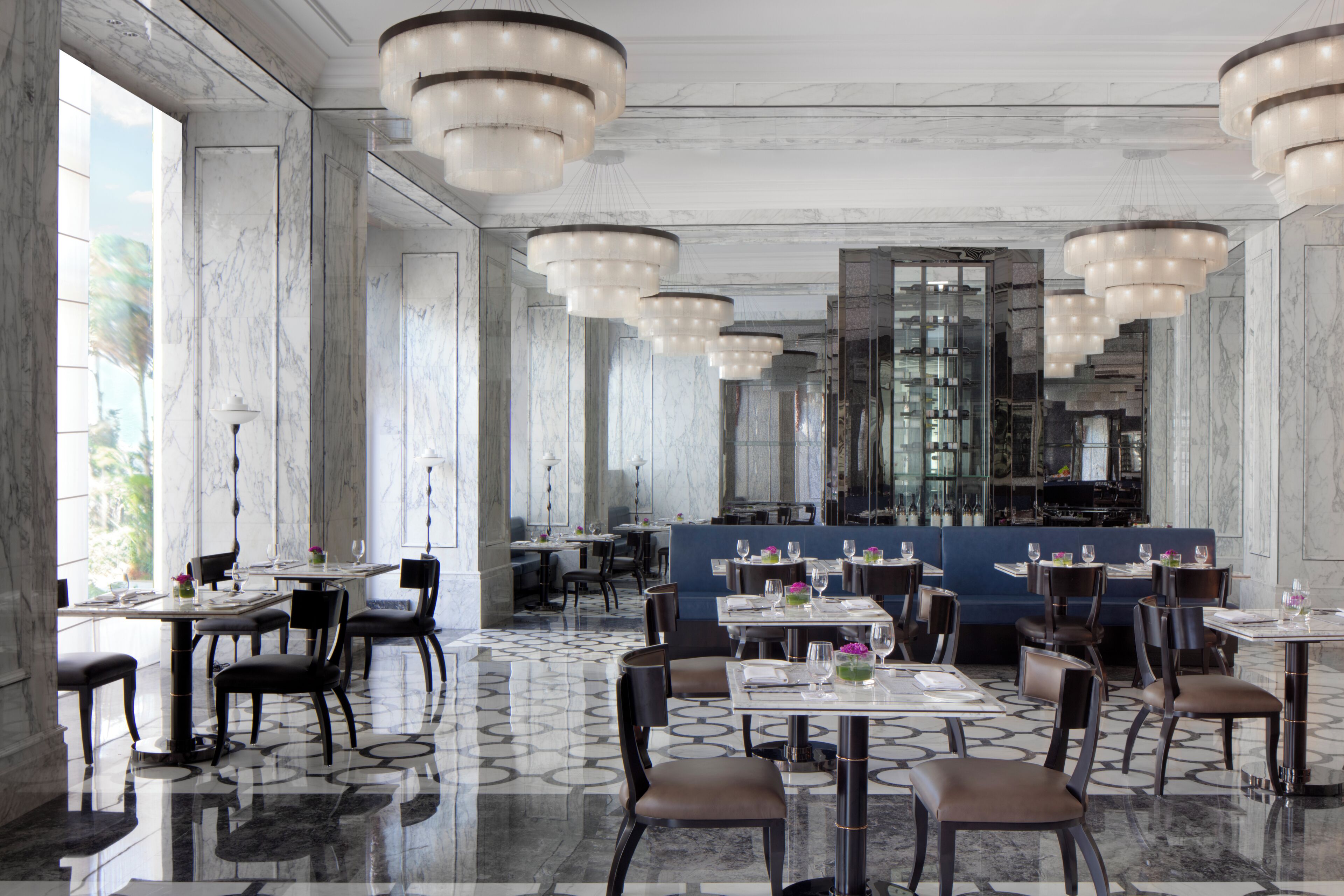 Un restaurant spacieux doté de sols en marbre, de nombreuses tables et de lustres modernes.