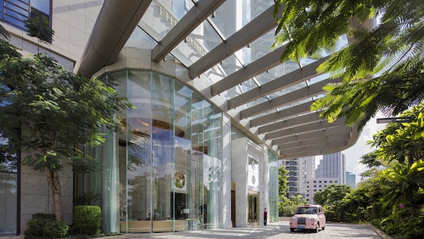 A modern building with a glass facade, a covered entrance, and a car parked in front. - The Langham, Haikou (Haikou)