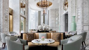 A luxurious hotel lobby with marble walls, a central seating area with a round table, and elegant chandeliers. - The Langham, Haikou (Haikou)
