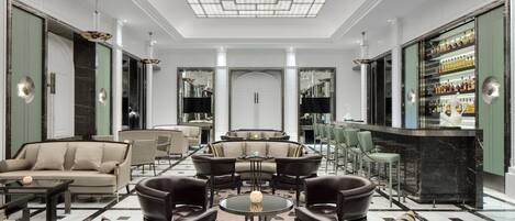 A spacious lobby with a central seating area, a bar, and a large mirror reflecting the space.