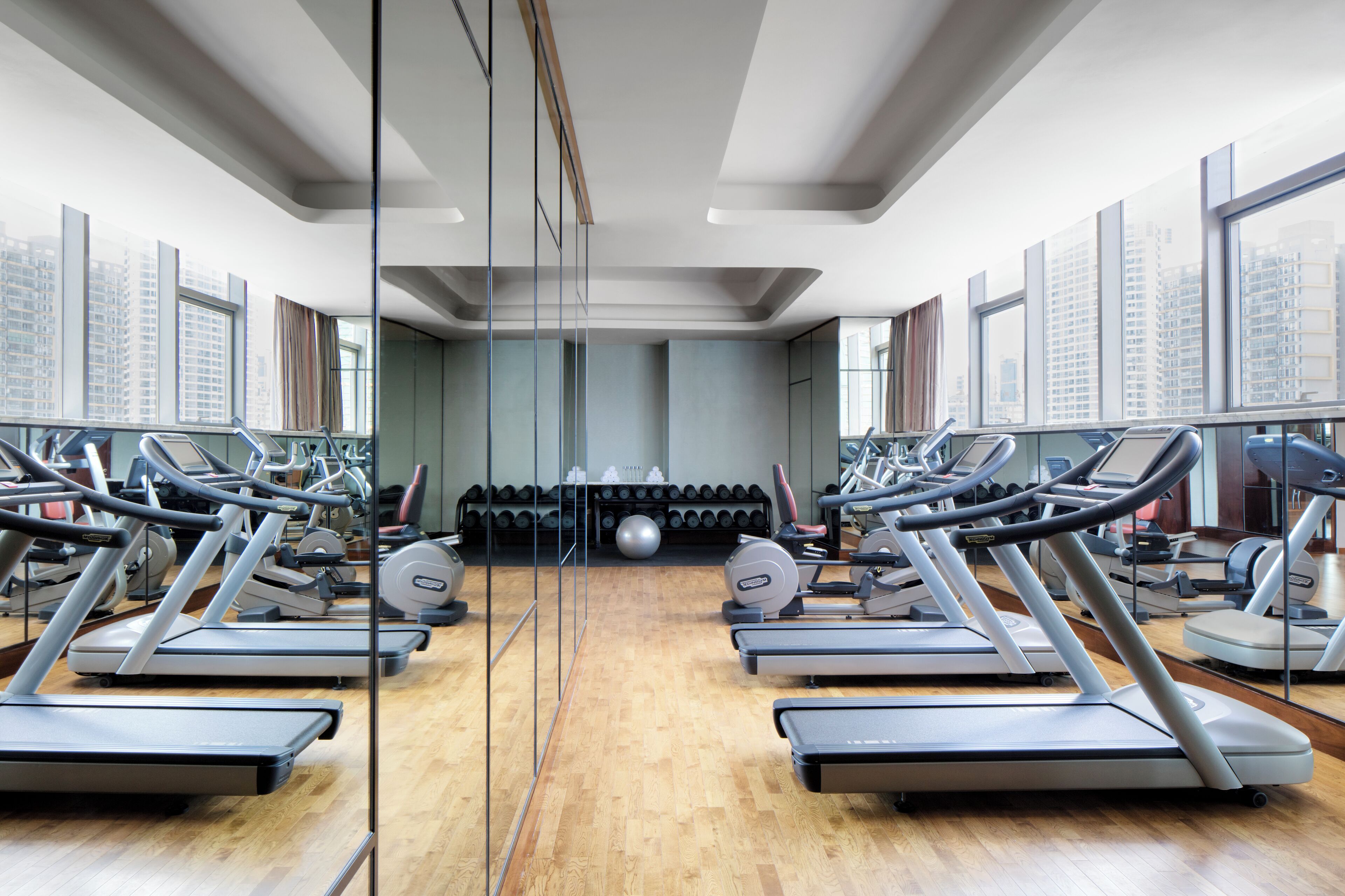 A gym with treadmills, weights, and a large mirror.