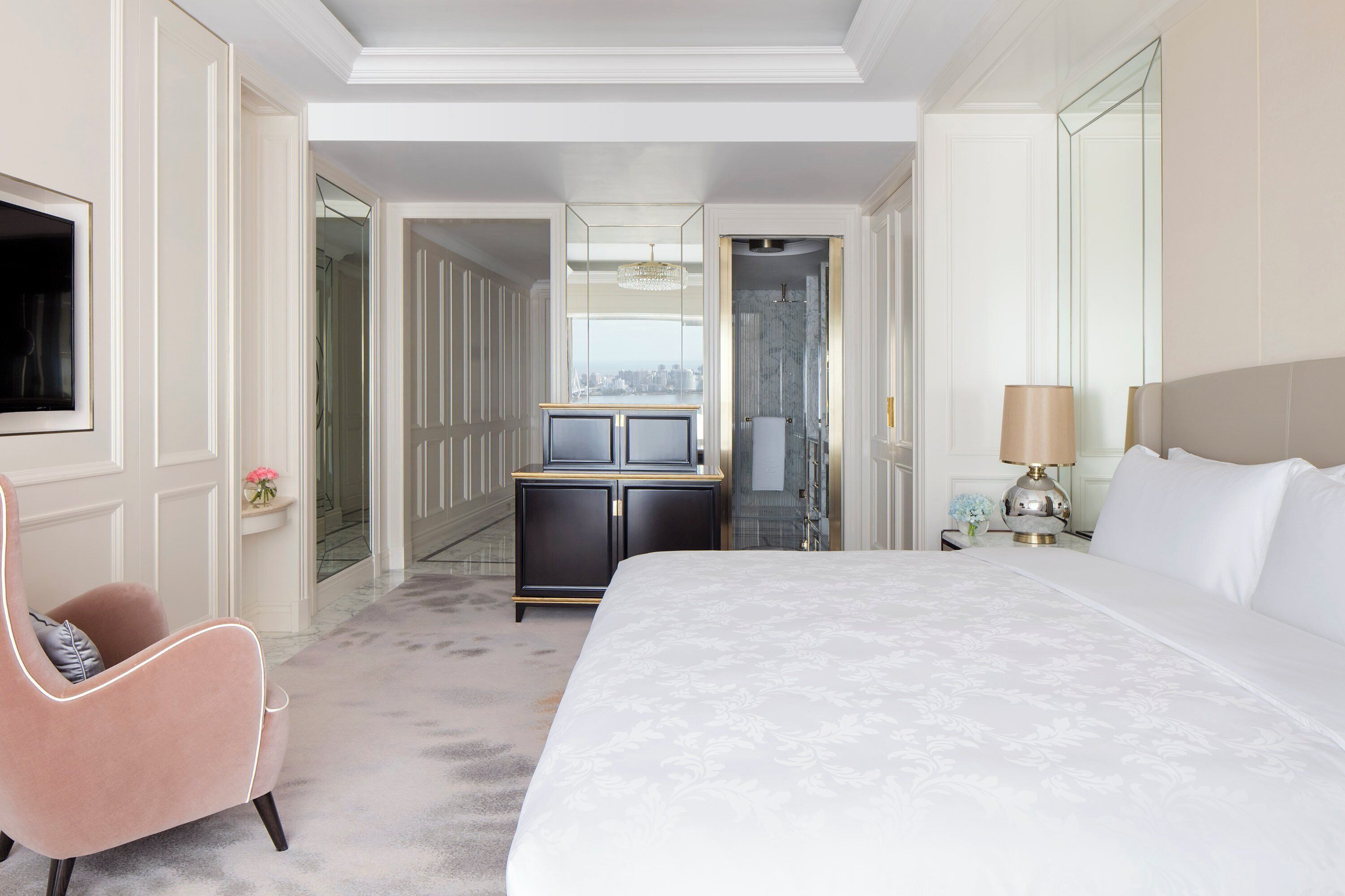 A hotel room with a large bed, a vanity with a mirror, a desk, and a chair.