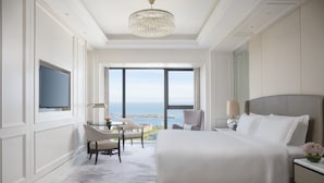 A hotel room with a large bed, a television, a desk with a chair, and a view of the sea. - The Langham, Haikou (Haikou)