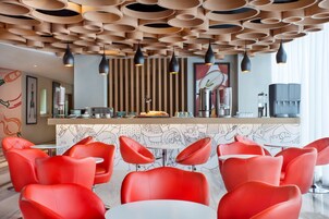 Interior moderno de restaurante con sillas rojas, un mostrador con productos alimenticios y un diseño de techo singular.