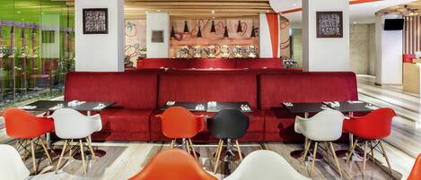 Un restaurante moderno con asientos rojos, mesas negras y una barra central.