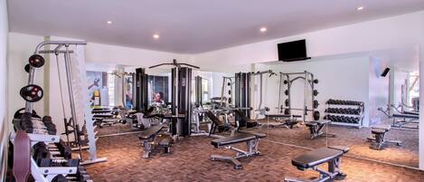 A gym with various exercise equipment, including dumbbells, benches, and weight machines.