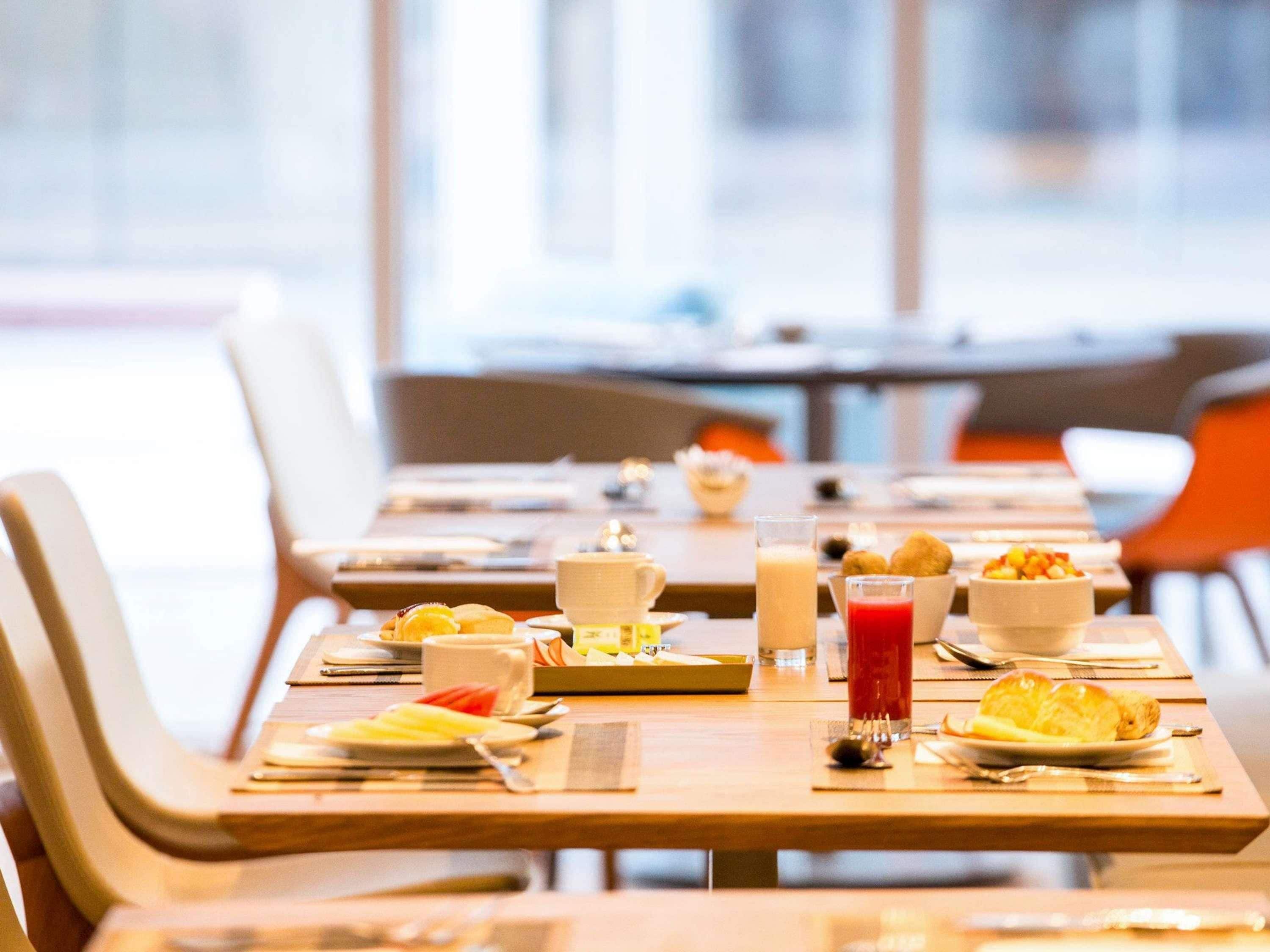 Une table mise pour le petit-déjeuner, avec des tables, des chaises et divers aliments et boissons.