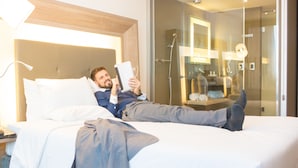 A hotel room with a bed, bedside lamp, and a glass shower enclosure. - Novotel RJ Porto Atlântico (Rio de Janeiro)