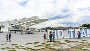 A modern architectural structure with a unique design, surrounded by a spacious plaza with geometric patterns and a large sign reading "RIO TEAM".