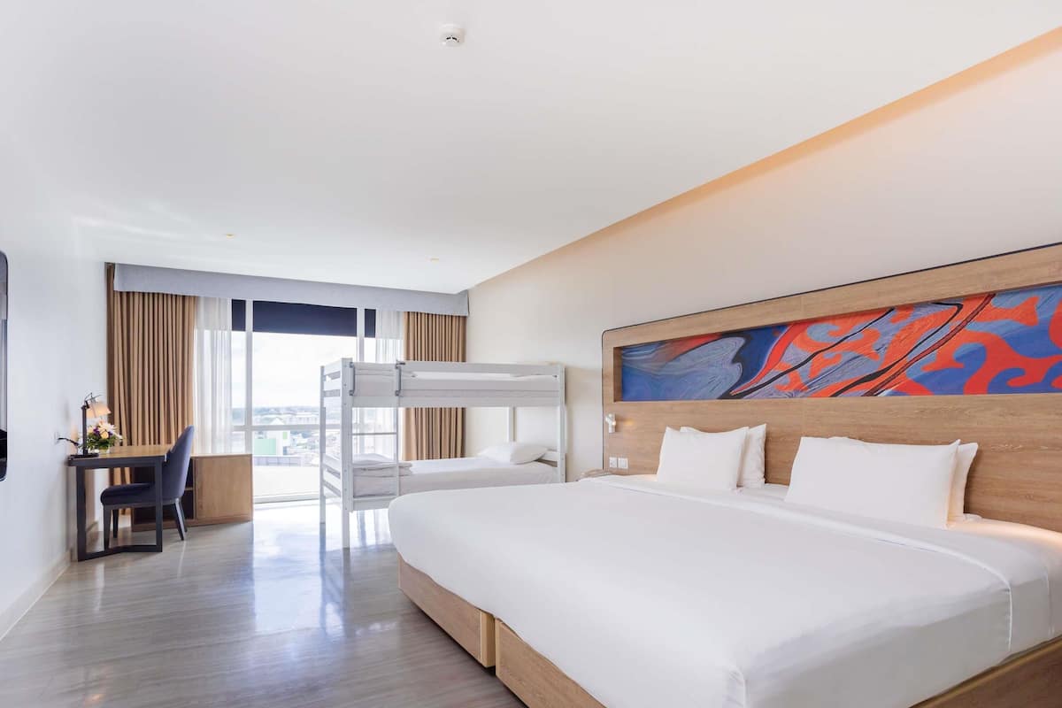 Quarto de hotel moderno com uma cama grande, uma mesa de trabalho e uma cama beliche.