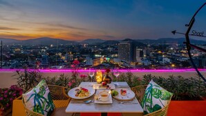 Mesa para dos con vista a la ciudad, iluminación exterior y un atardecer.
