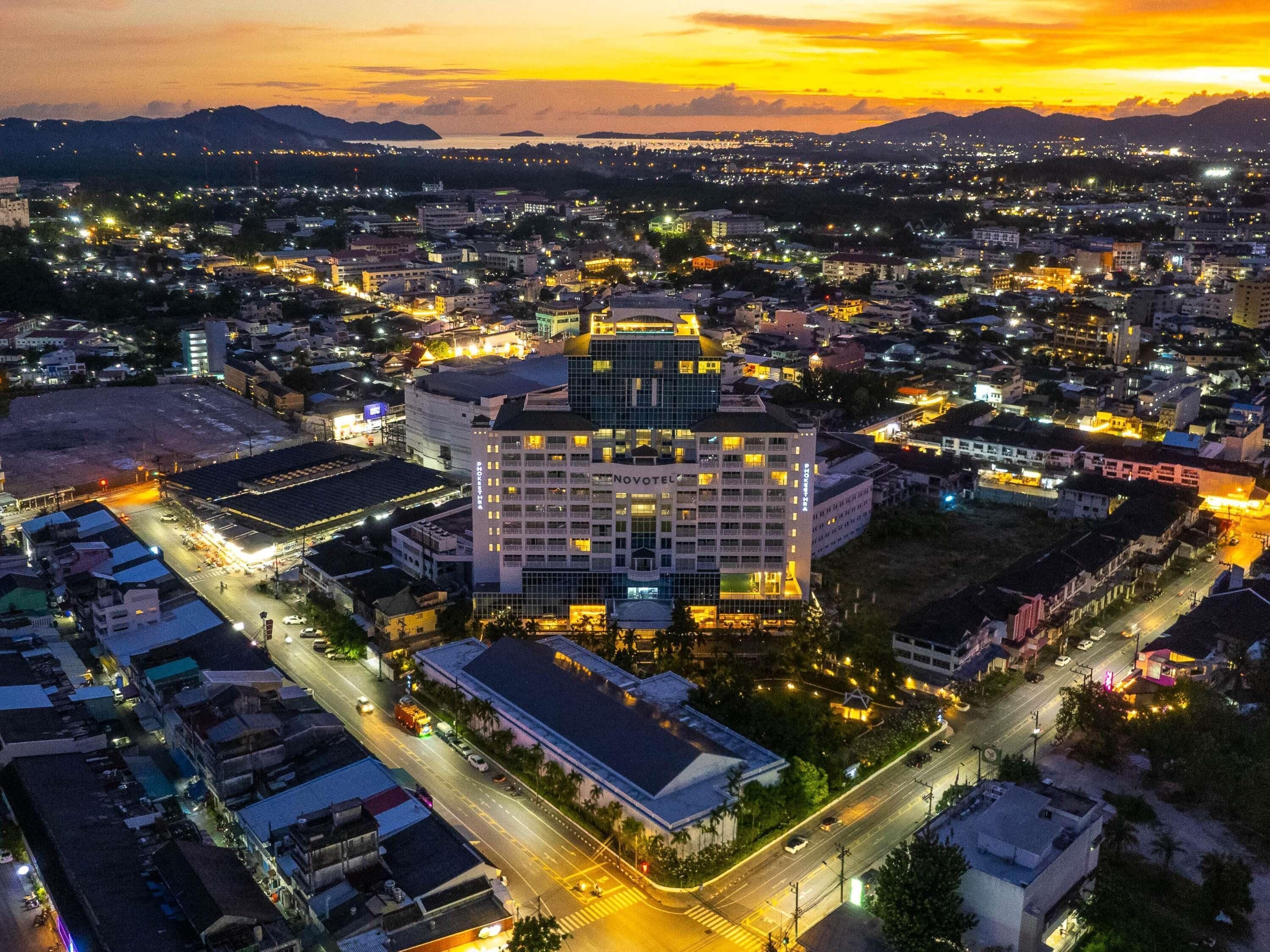 A hotel with multiple floors, a central courtyard, and a view of the surrounding cityscape at dusk.