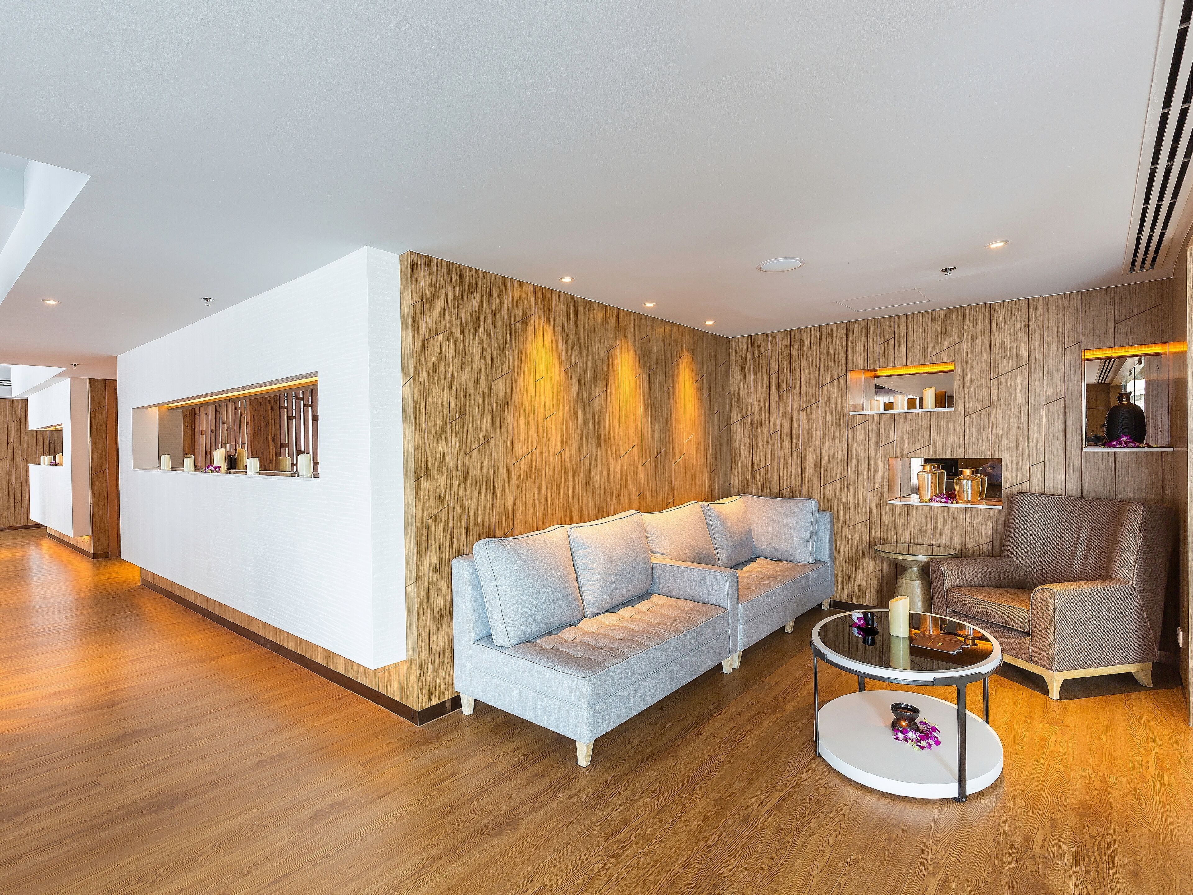 Una sala de estar moderna con un sofá azul claro, un sillón gris y una mesa de centro redonda.