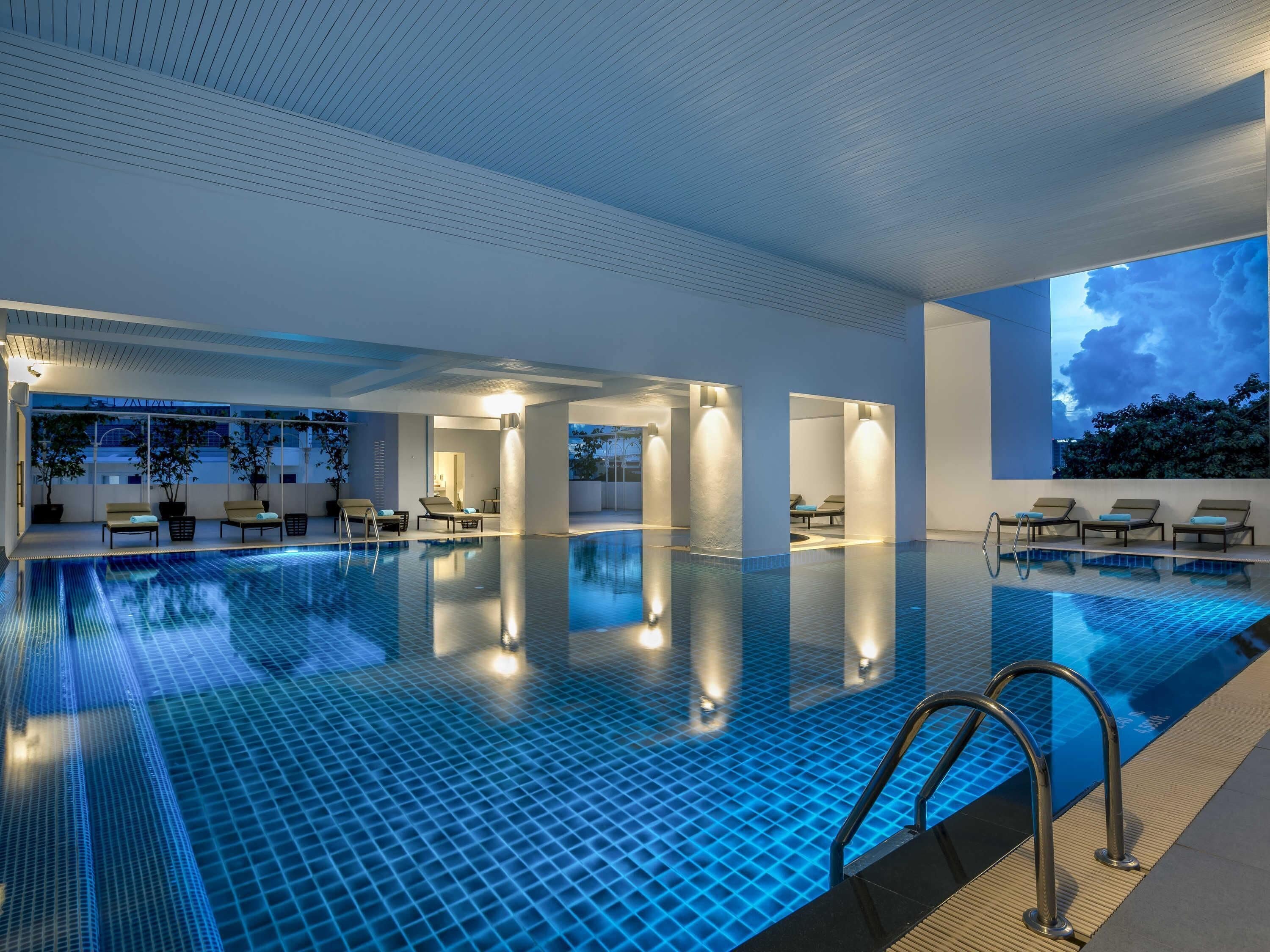 Una piscina techada, una piscina al aire libre, sombrillas