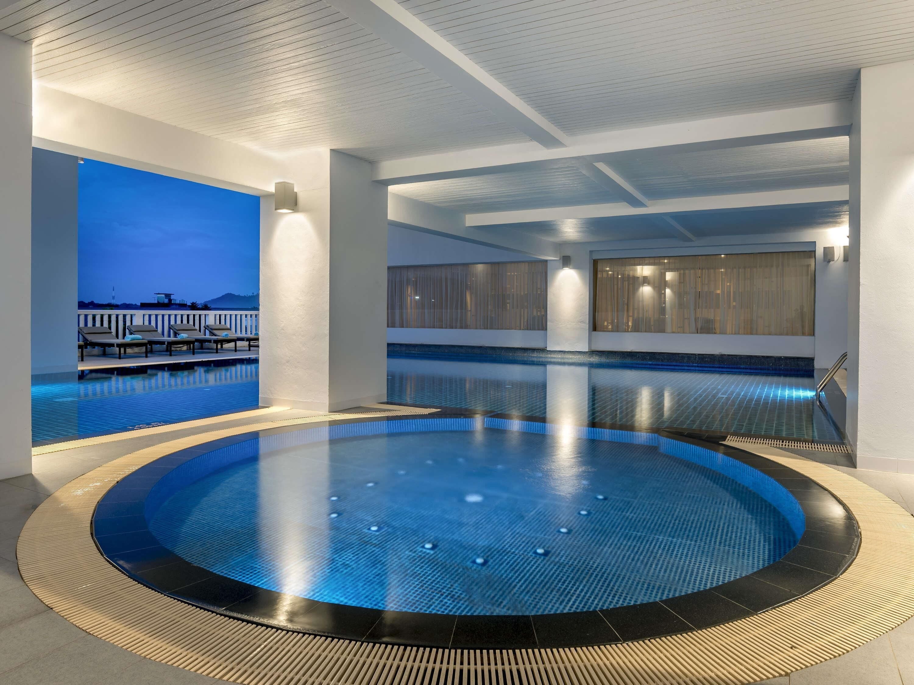 Una piscina techada, una piscina al aire libre, sombrillas