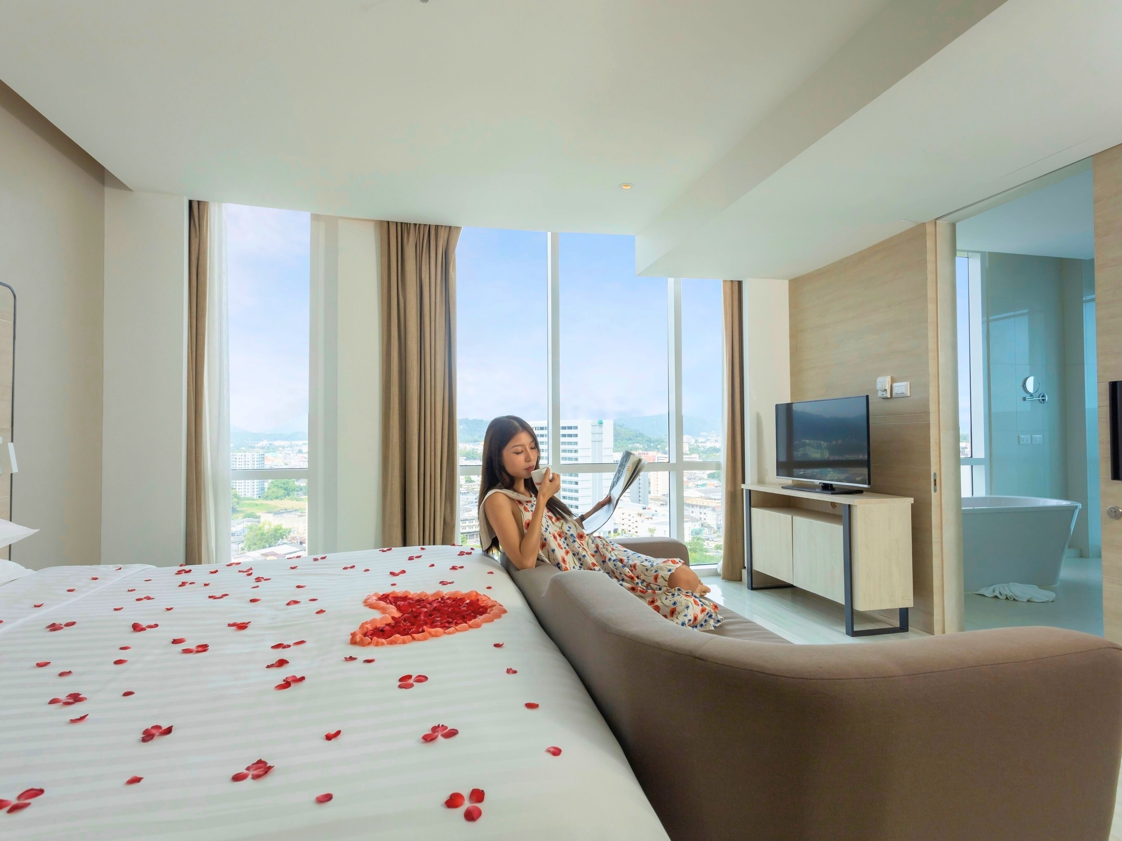 A hotel room with a large bed, a TV, and a view of the city.