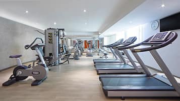 Un gimnasio con cintas de correr, elípticas y equipo de pesas.