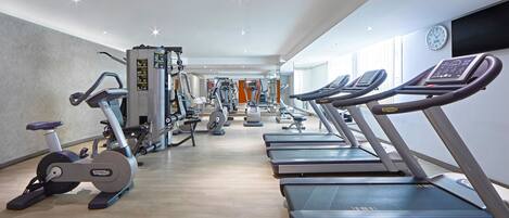 Un gimnasio con cintas de correr, elípticas y equipo de pesas.