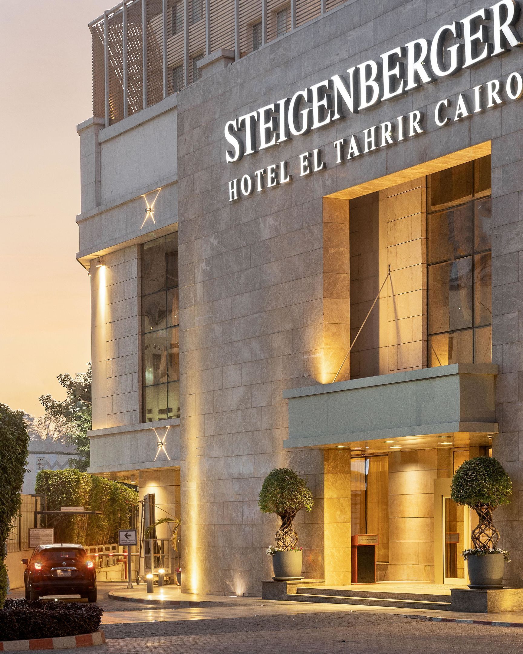 Fachada moderna de un hotel con amplias ventanas y un cartel llamativo que dice "STEIGENBERGER HOTEL EL TAHRIR CAIRO".