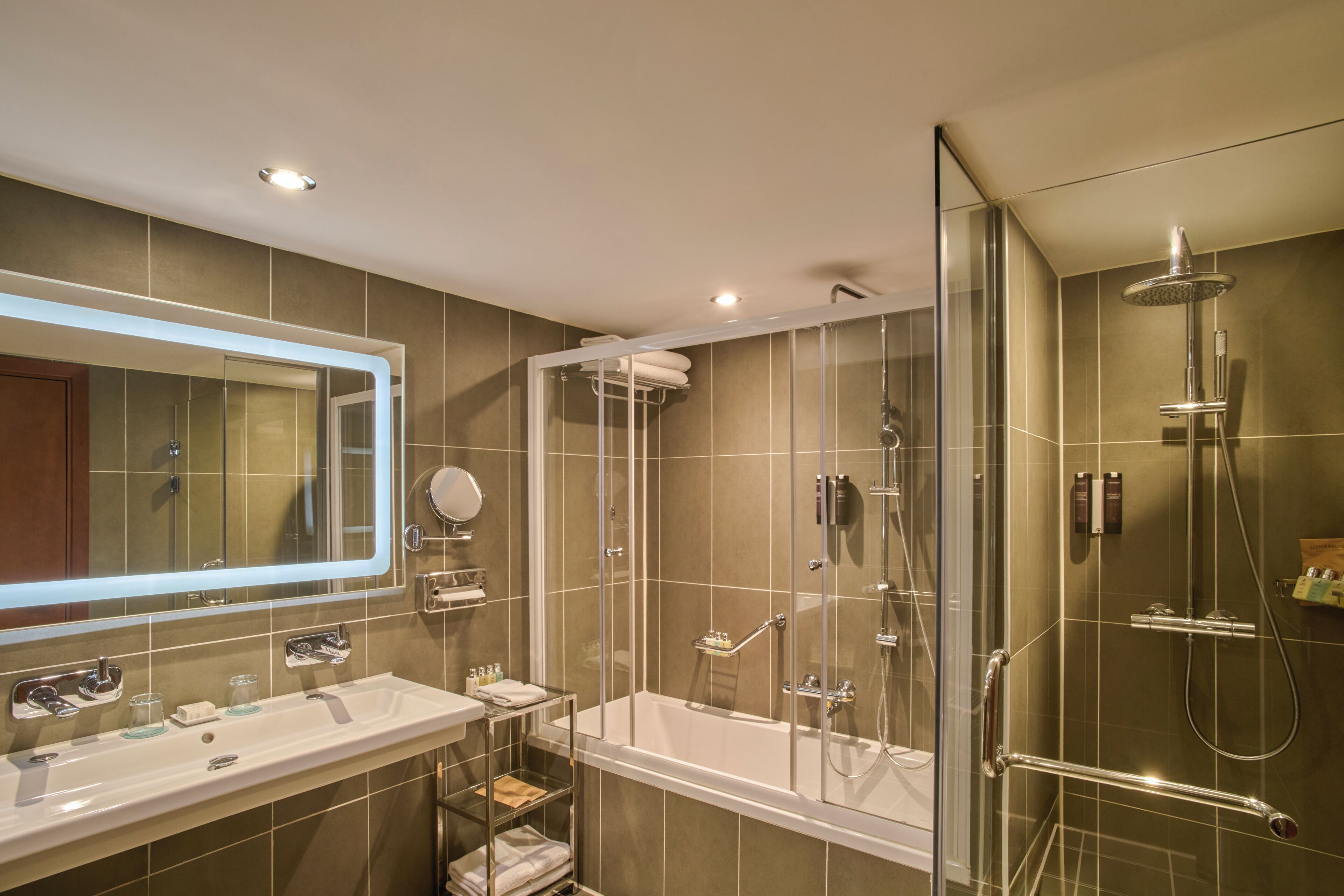 Une salle de bain moderne avec une douche à parois de verre, un meuble-lavabo à deux vasques et un grand miroir.