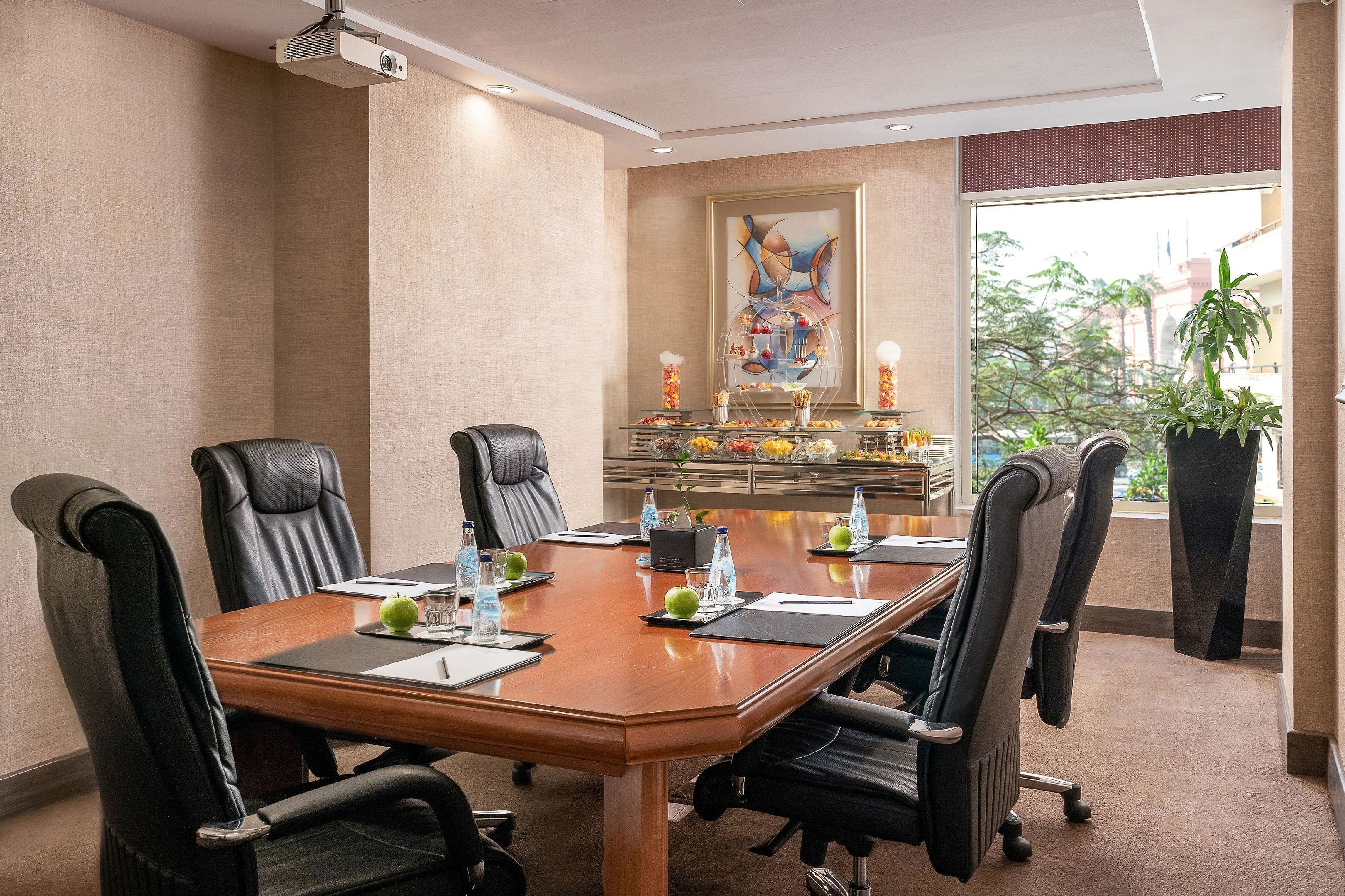 A conference room with a long table, six chairs, water bottles, and a projector.