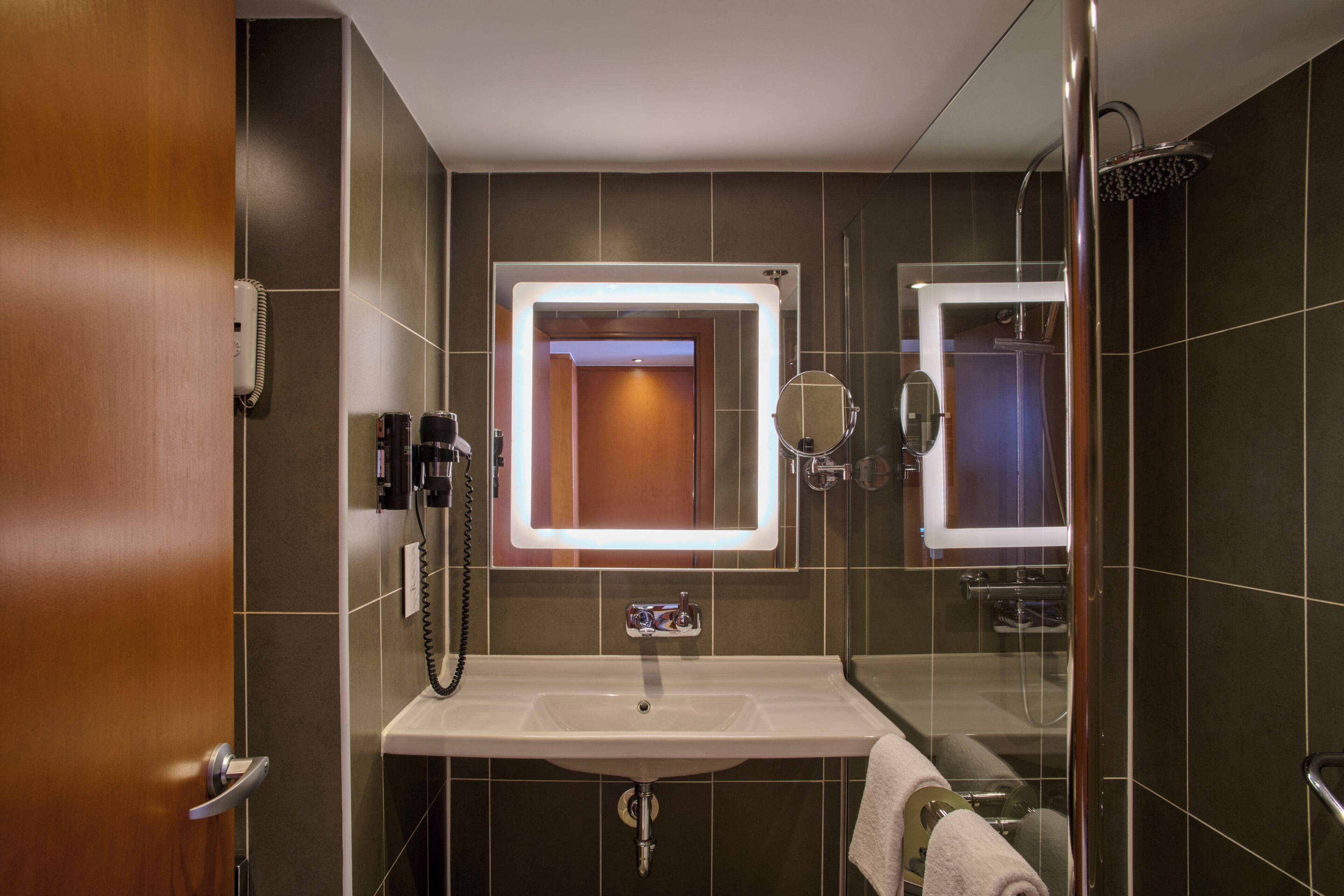 Une salle de bain moderne avec une douche à parois de verre, un meuble-lavabo avec un miroir et un porte-serviettes.