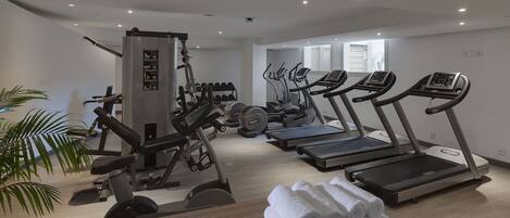 A modern gym with treadmills, weight machines, and dumbbells.