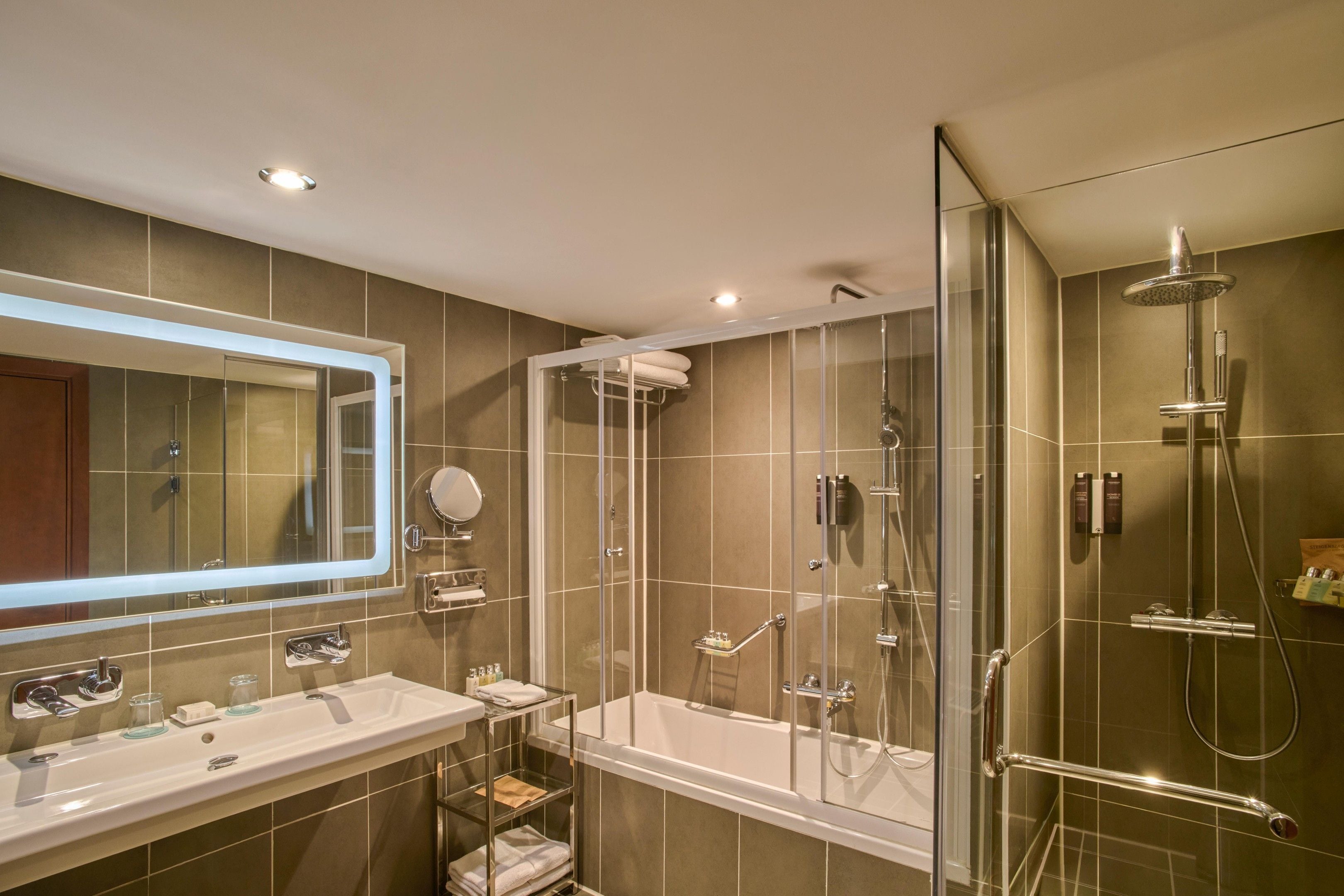 Une salle de bain moderne avec une douche à parois de verre, un meuble-lavabo à deux vasques et un grand miroir.
