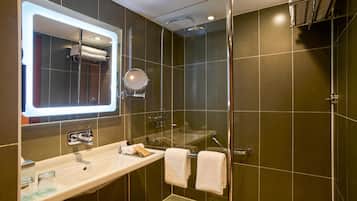A modern bathroom with a glass-enclosed shower, a vanity with a mirror, and a towel rack.