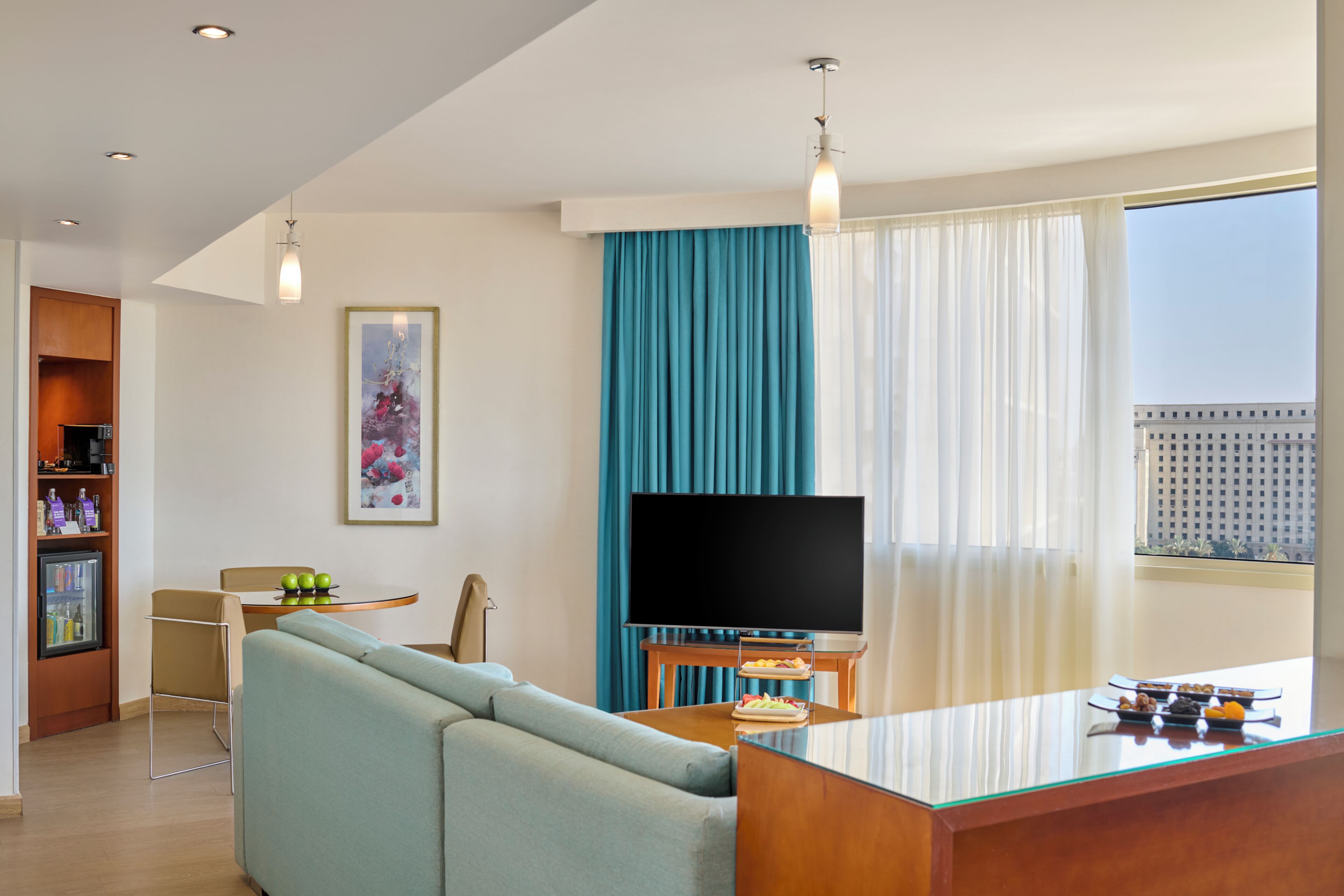 Ein modernes Wohnzimmer mit einer Couch, einem Flachbildfernseher, einem Couchtisch und einem Essbereich mit einem kleinen Tisch und Stühlen.