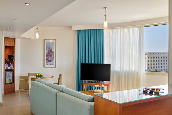 A modern living room with a sofa, a flat-screen TV, a coffee table, and a dining area with a small table and chairs. - Steigenberger Hotel El Tahrir Cairo (Cairo)
