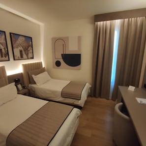 A hotel room with two beds, a desk, a chair, and a wall-mounted artwork. - Vittoria Parc Hotel (Bari)