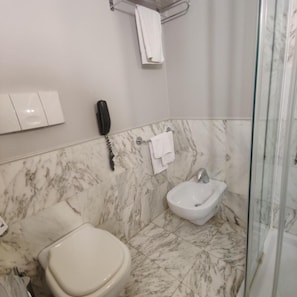 A bathroom with a toilet, bidet, and glass shower enclosure. - Vittoria Parc Hotel (Bari)