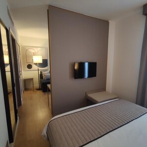 A hotel room with a bed, a television mounted on the wall, a bedside table, and a lamp. - Vittoria Parc Hotel (Bari)
