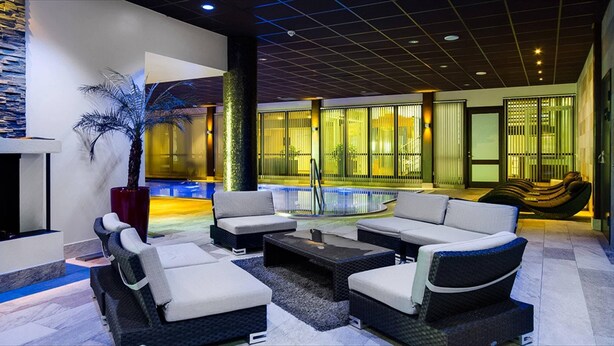 Un espace de détente moderne avec une piscine, des sièges extérieurs et une plante décorative.